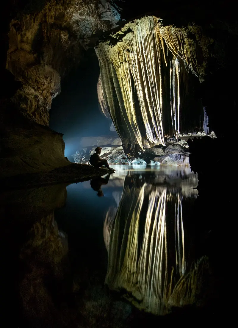 A caver dwarfed by a cave chamber